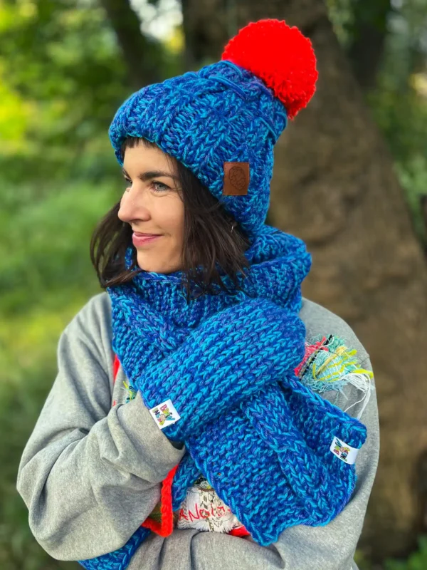 Stylowa niebieska czapka z pomarańczowym pomponem, ręcznie tworzona przez seniorki z Poznania.